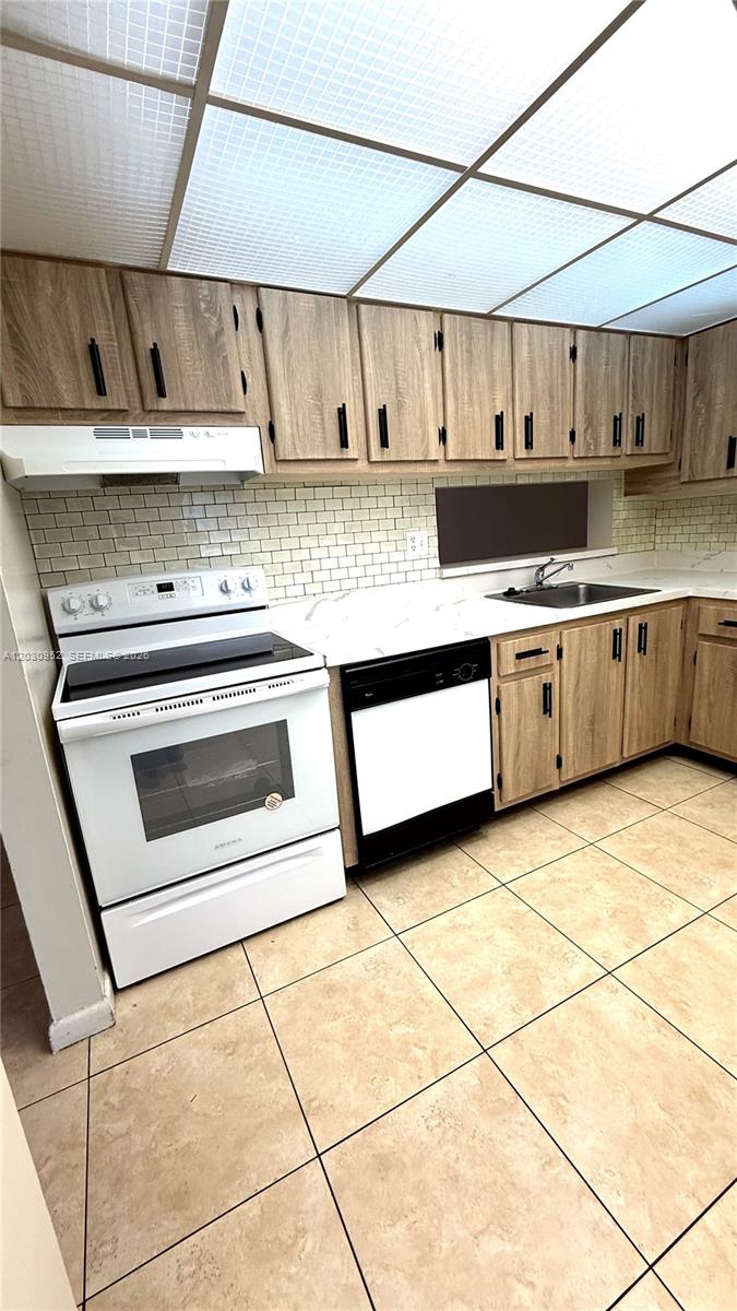 A kitchen features light wood cabinets, white appliances, a subway tile backsplash, and tiled flooring — 8540 SW 133rd Ave Rd # 422, Miami FL 33183, MIAMI, FL