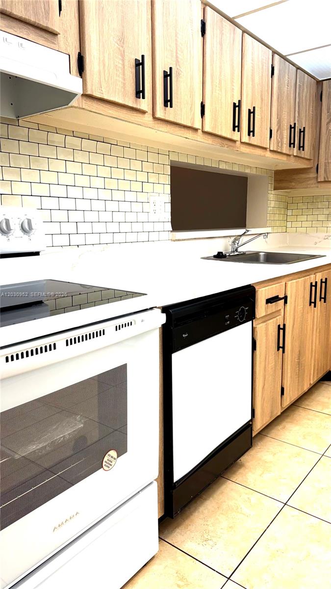 A kitchen features light wood cabinets, white countertops, a subway tile backsplash, and black appliances — 8540 SW 133rd Ave Rd # 422, Miami FL 33183, MIAMI, FL