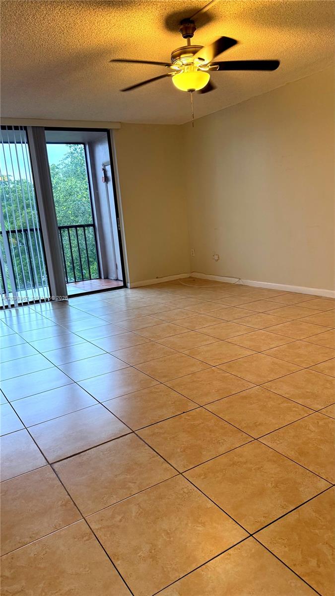 An empty room features beige tile flooring, a ceiling fan, and a sliding glass balcony door — 8540 SW 133rd Ave Rd # 422, Miami FL 33183, MIAMI, FL