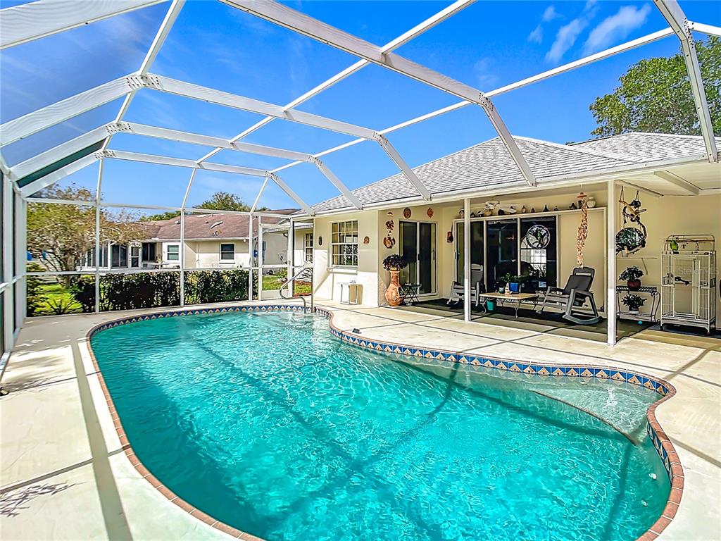 A swimming pool with a decorative tile border is enclosed by a screened lanai — 4812 ALFA TERRACE, NORTH PORT, FL