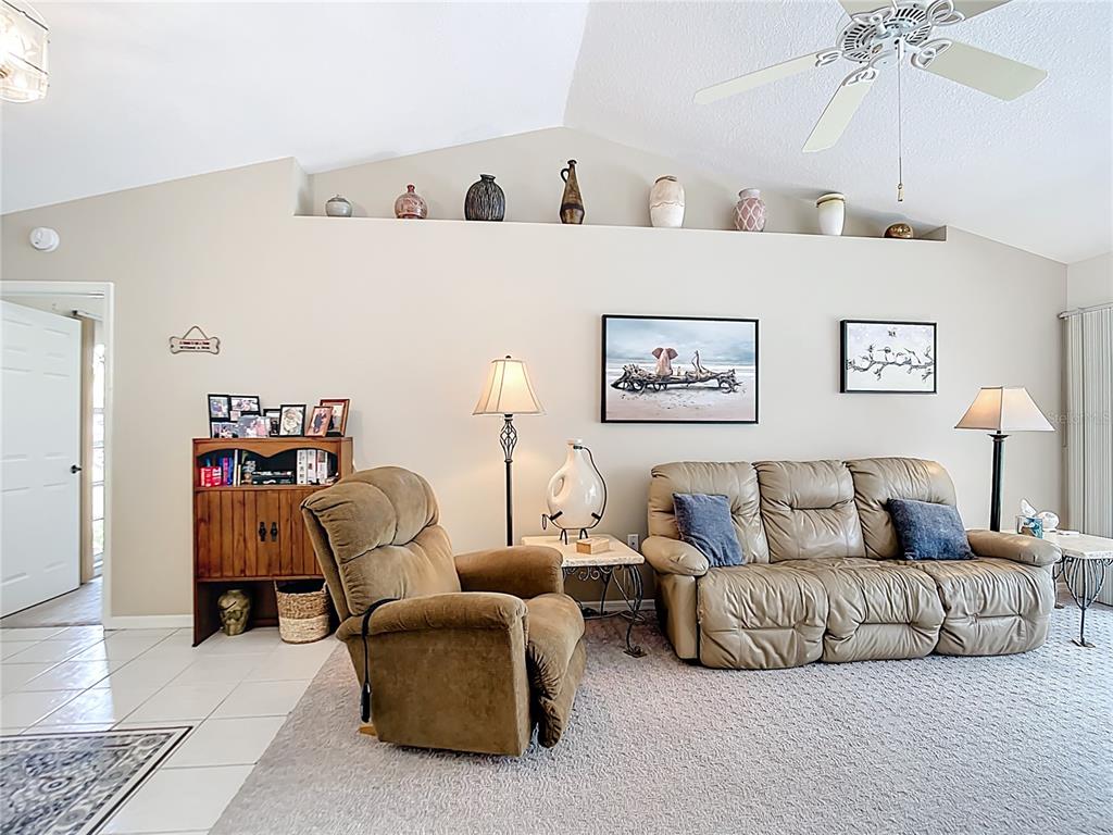 A living room features a vaulted ceiling, a ledge with decorative vases, and beige furniture — 4812 ALFA TERRACE, NORTH PORT, FL