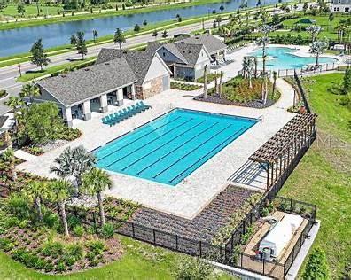 An aerial view shows a community swimming pool with a pergola and adjacent clubhouse building — 12163 CATTLESIDE DRIVE, RIVERVIEW, FL