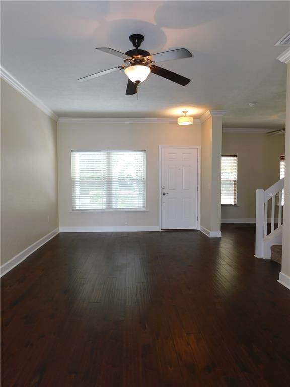 An empty room with dark wood flooring, a window, and a hanging chandelier — 5156 NW 21ST DRIVE, GAINESVILLE, FL