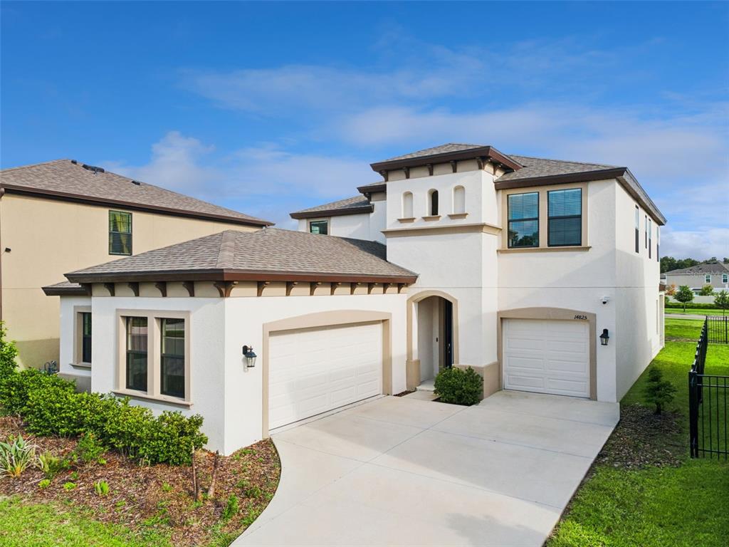 A two-story stucco house features a three-car garage, a concrete driveway, and a tiled roof — 14825 PADDOCK POND AVENUE, LITHIA, FL