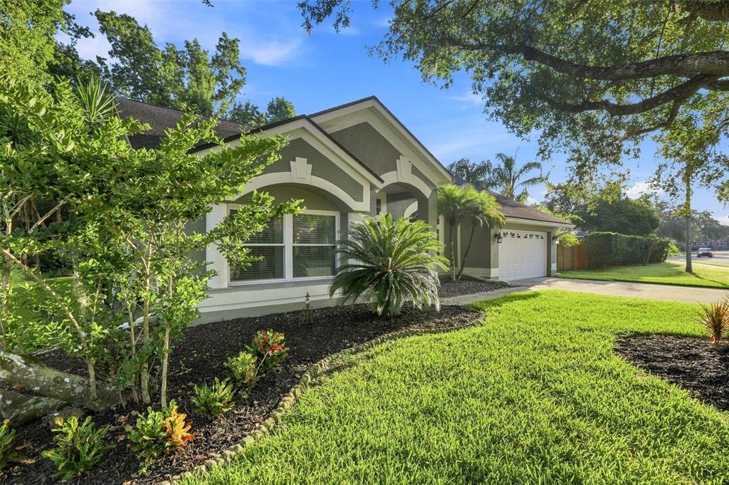 A single-story house with a green exterior, a two-car garage, and a landscaped front yard — 2200 EKANA DRIVE, OVIEDO, FL