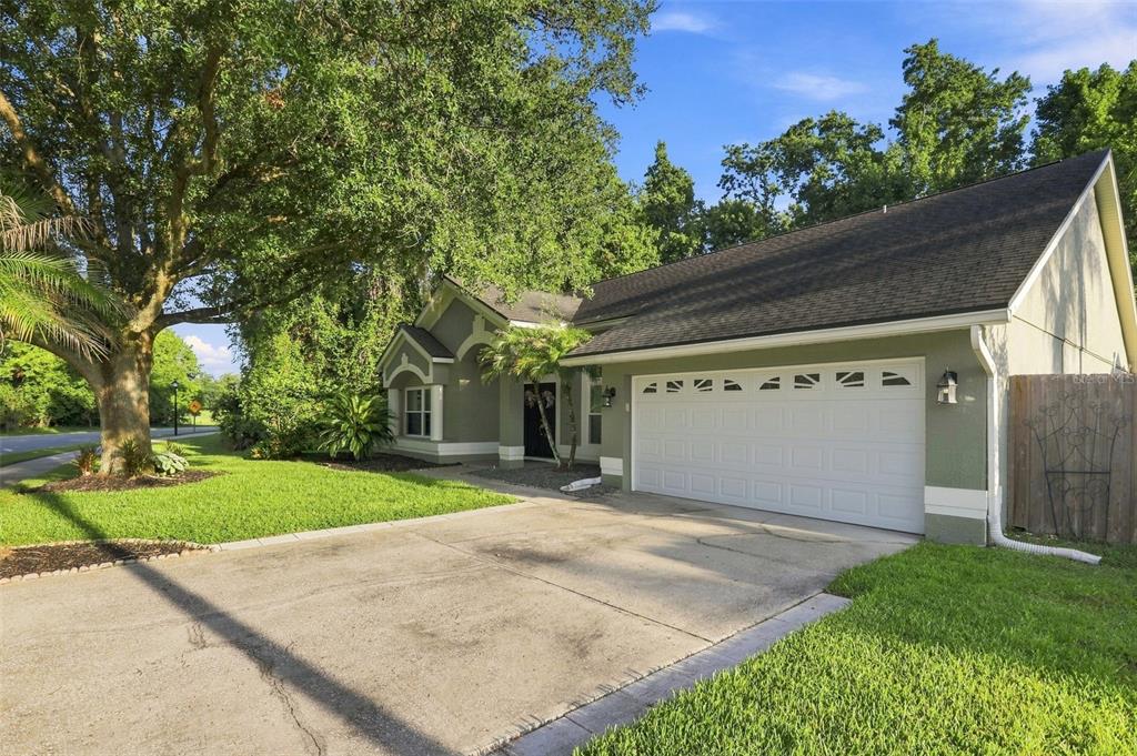 A single-story house with a green exterior, a two-car garage, and a large oak tree — 2200 EKANA DRIVE, OVIEDO, FL