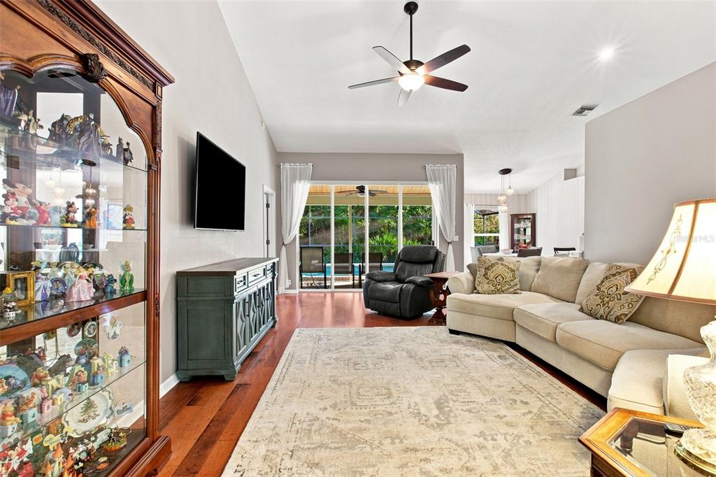 A living room features a large display cabinet, a sectional sofa, and sliding glass doors — 2200 EKANA DRIVE, OVIEDO, FL