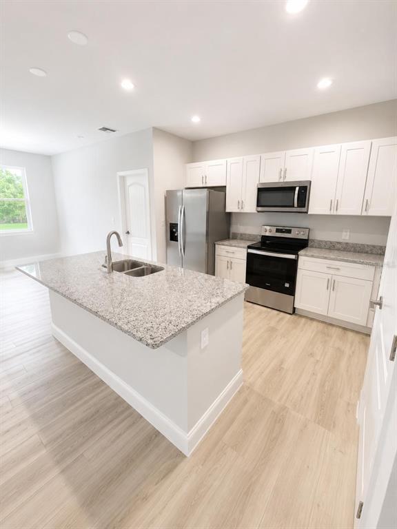 A kitchen features white cabinets, granite countertops, stainless steel appliances, and a central island — 1602 PICKEREL COURT, POINCIANA, FL