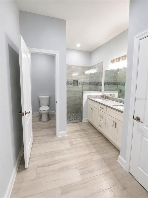 A bathroom with a white vanity, a glass-enclosed shower, and a separate toilet closet — 1602 PICKEREL COURT, POINCIANA, FL