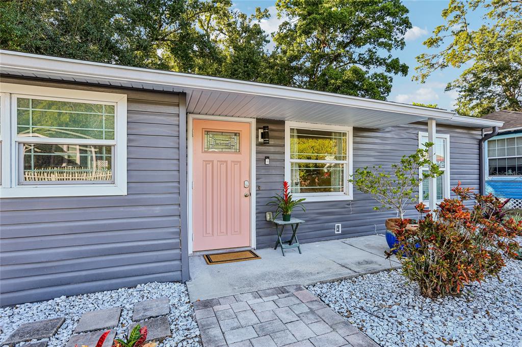 A gray-sided house exterior features a light pink front door and a stone walkway — 4104 N SEMINOLE AVENUE, TAMPA, FL