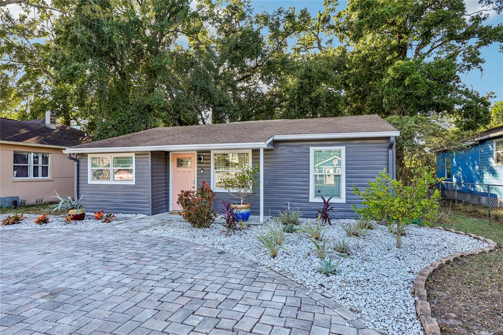 A single-story house with dark gray siding, a pink front door, and a paved driveway — 4104 N SEMINOLE AVENUE, TAMPA, FL