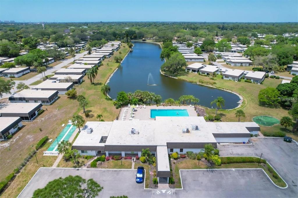 An aerial view shows a community clubhouse with a pool, pond, and surrounding residential units — 3960 LAKESIDE ROAD UNIT 156, SARASOTA, FL
