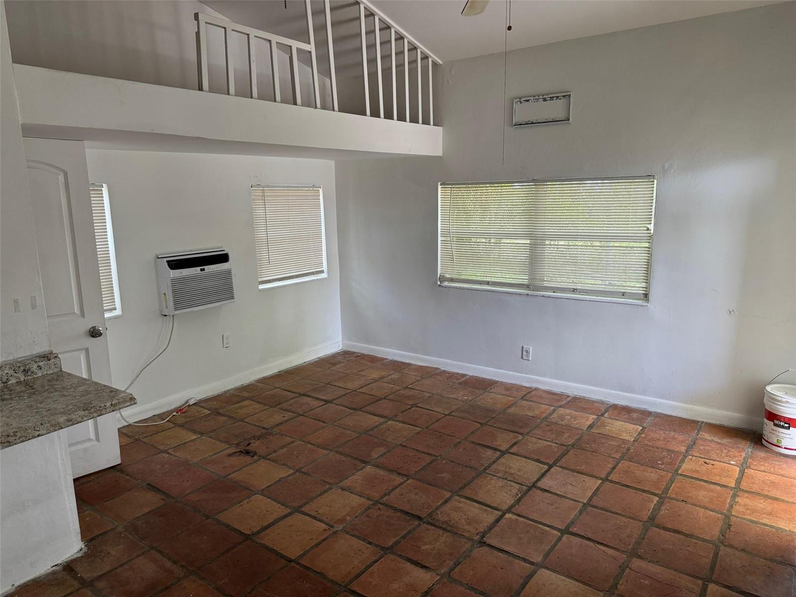 An interior view of a room with terracotta tile flooring, a loft area, and windows — 8261 NW 1st Place # 3, Miami FL 33150, MIAMI, FL
