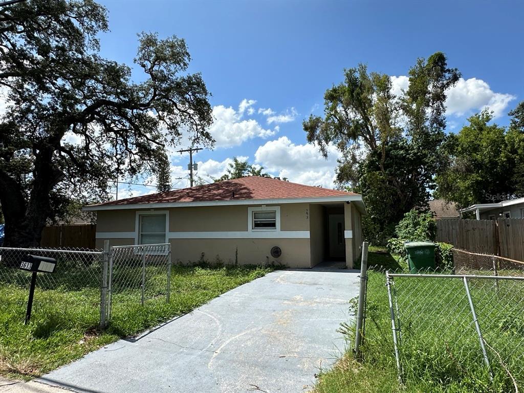 A single-story house with a tan exterior, a red roof, and a concrete driveway — 3613 E CHELSEA STREET, TAMPA, FL