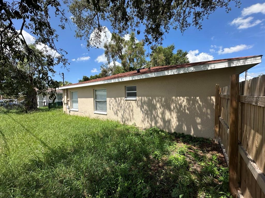 The exterior side view of a tan house features a red roof and windows — 3613 E CHELSEA STREET, TAMPA, FL