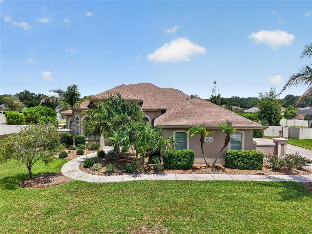 A single-story house with a brown shingled roof, tan stucco walls, and a landscaped front yard — 3986 SE 43RD CIRCLE, OCALA, FL
