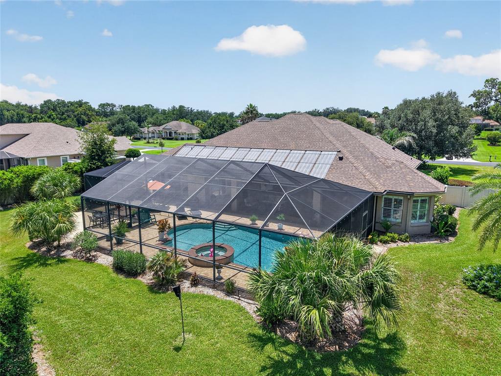 An aerial view shows a house with a screened-in pool and spa in the backyard — 3986 SE 43RD CIRCLE, OCALA, FL