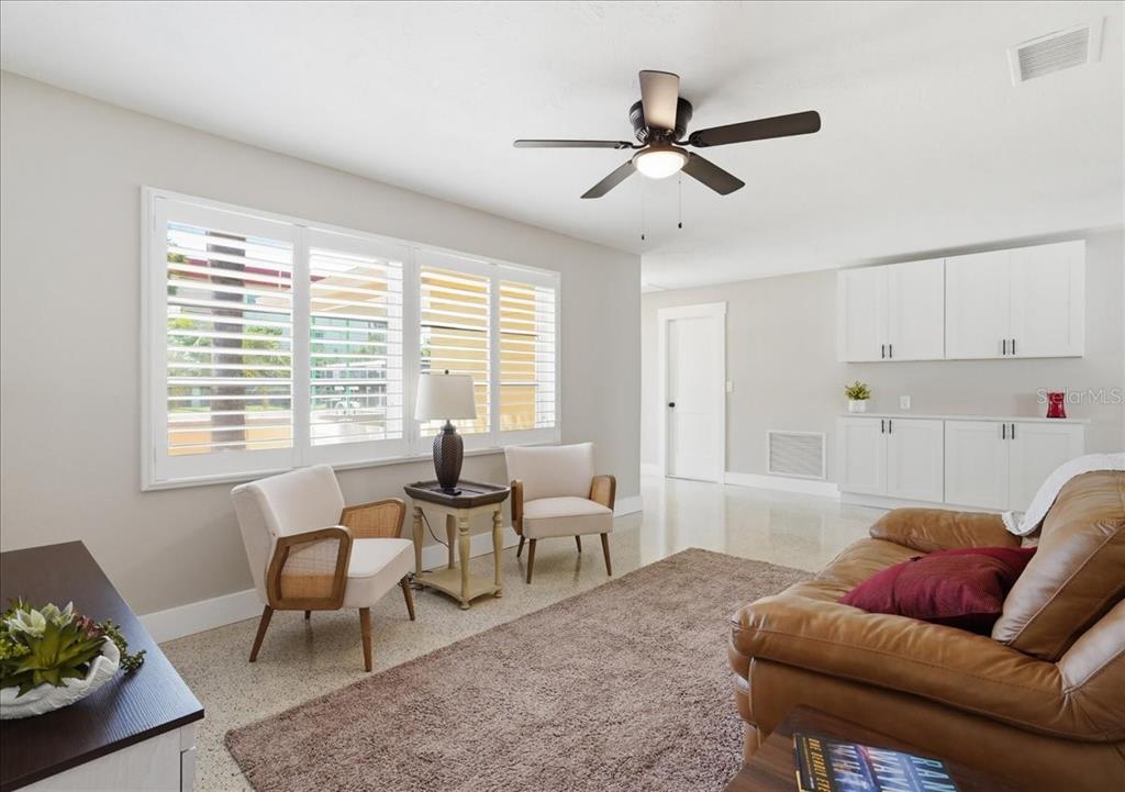 A living room features a ceiling fan, white cabinetry, two armchairs, and a leather sofa — 3014 58TH STREET S, GULFPORT, FL