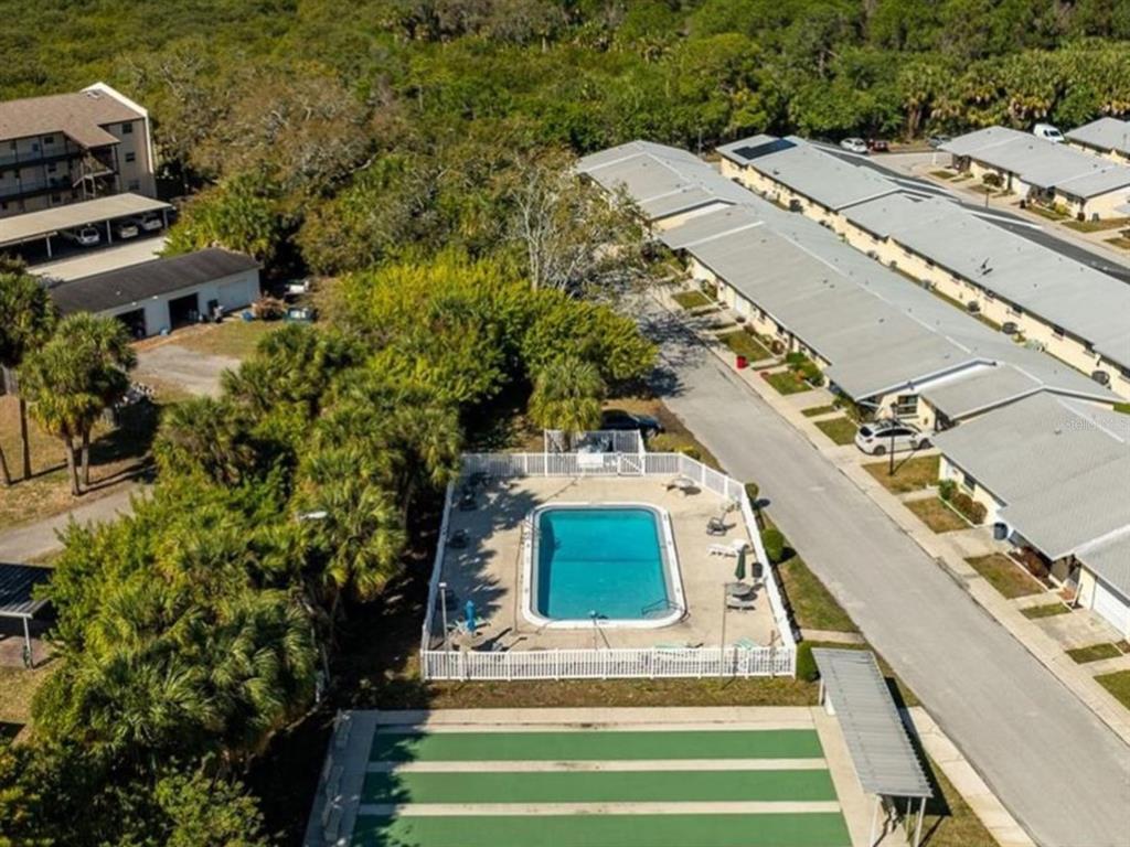 An aerial view shows a swimming pool, shuffleboard court, and adjacent residential buildings — 4954 BITNER STREET, NEW PORT RICHEY, FL
