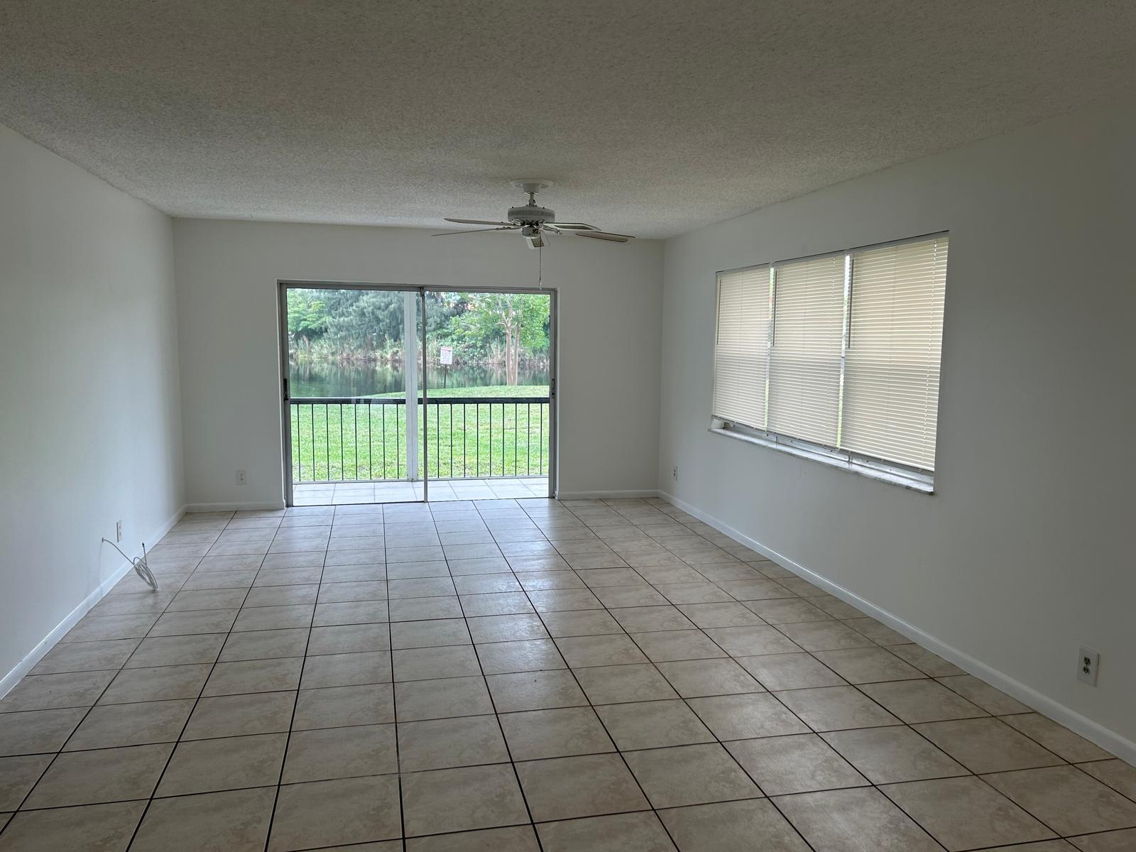 An empty living room with tiled floors, a ceiling fan, and sliding doors to a patio — 3300 Spanish Moss Terrace, Lauderhill FL 33319, LAUDERHILL, FL