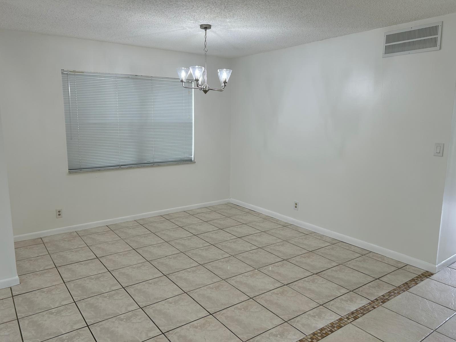 An empty dining room with white walls, tile flooring, a window with blinds, and a chandelier — 3300 Spanish Moss Terrace, Lauderhill FL 33319, LAUDERHILL, FL