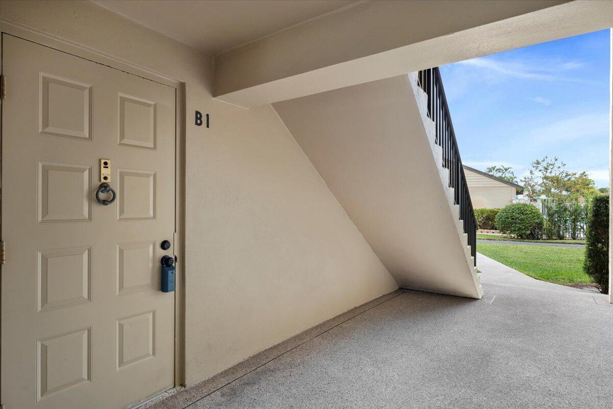 A white door labeled B1 is located under a concrete staircase leading outdoors — 708 Sunny Pine Way # B1, FL 33415, FL