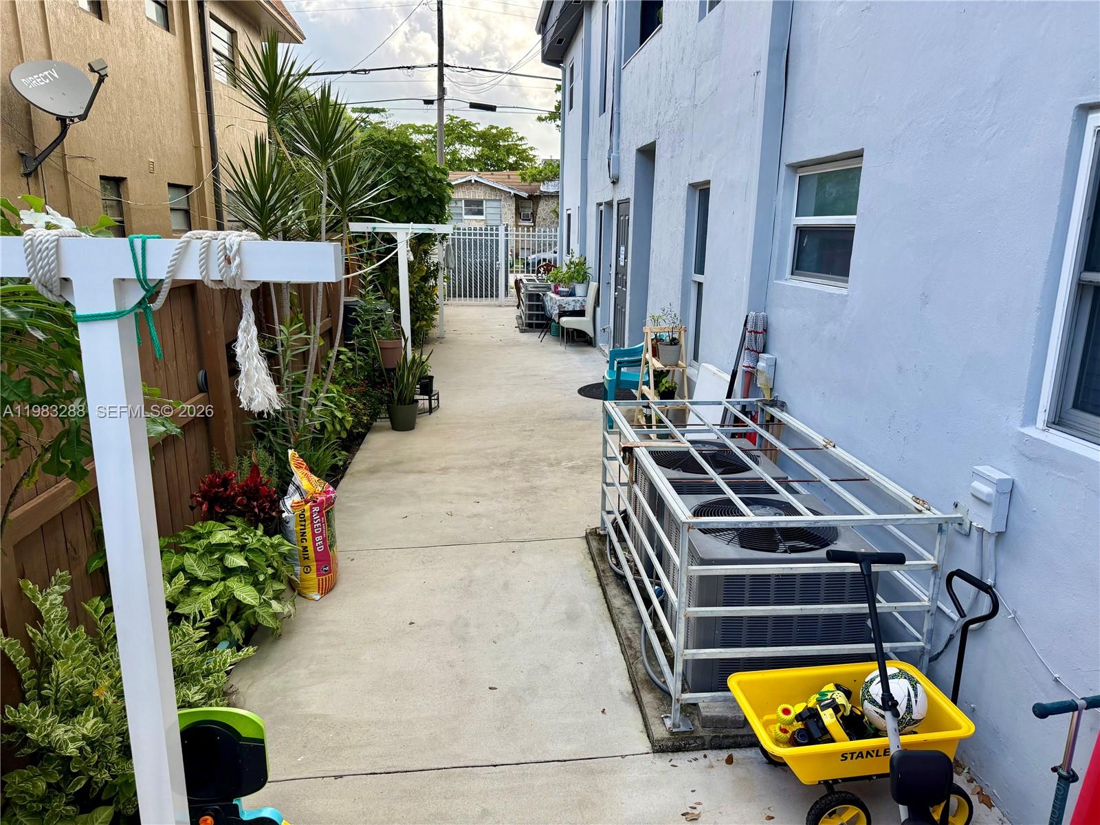 A narrow concrete walkway runs between a wooden fence and a light blue building — 1305 NW 4th St # 3, Miami FL 33125, MIAMI, FL