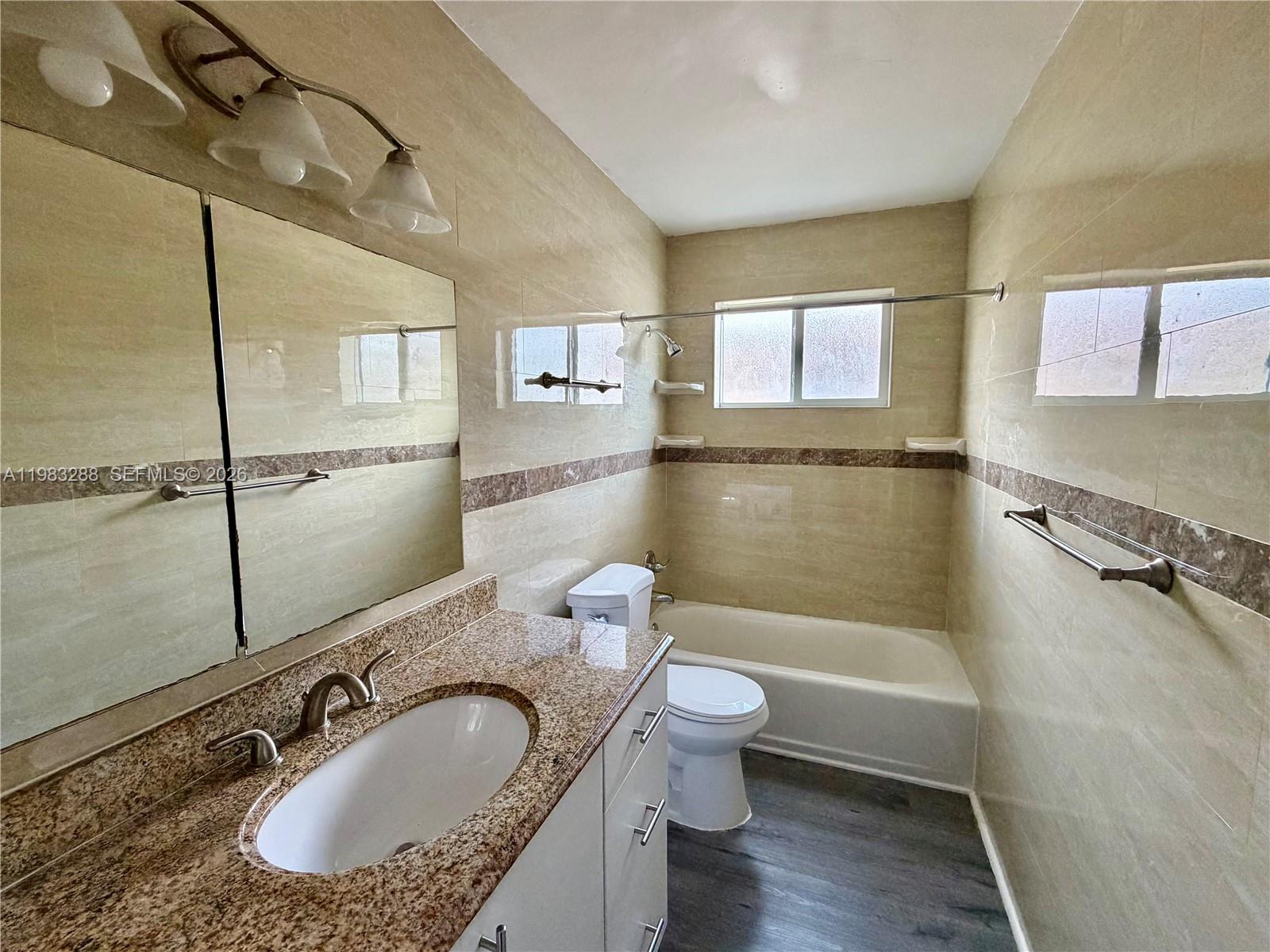 A bathroom features a granite vanity, a white toilet, and a tiled tub-shower combination — 1305 NW 4th St # 3, Miami FL 33125, MIAMI, FL