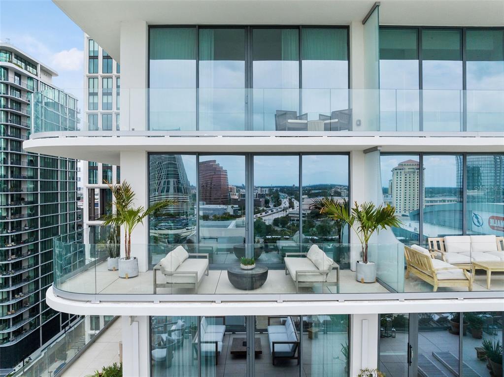 A multi-story building exterior featuring modern balconies with glass railings and outdoor lounge furniture — 1000 WATER STREET UNIT 1103, TAMPA, FL