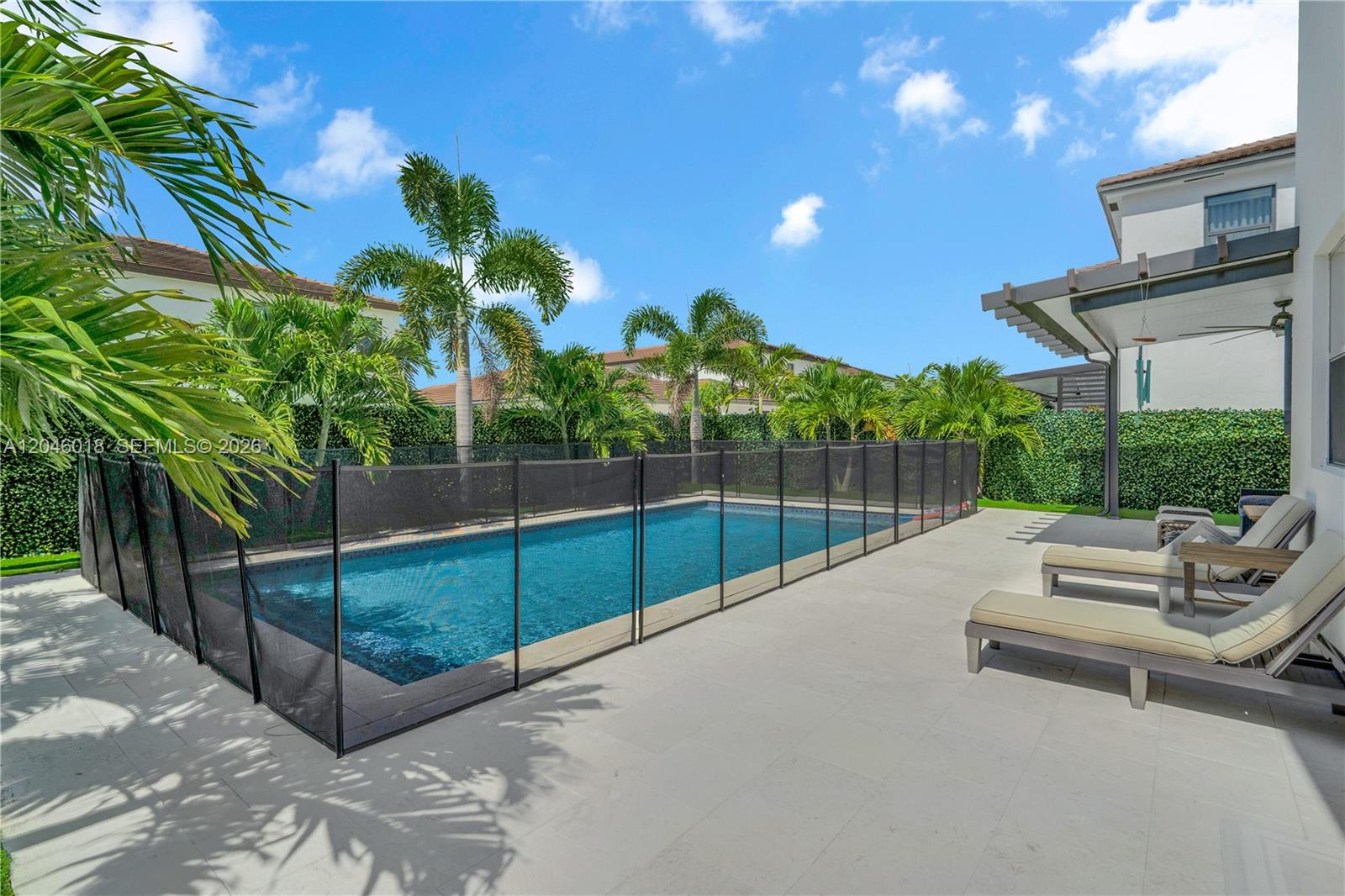 A rectangular swimming pool with a black safety fence sits on a paved patio — 12924 SW 229th St, Miami FL 33170, MIAMI, FL