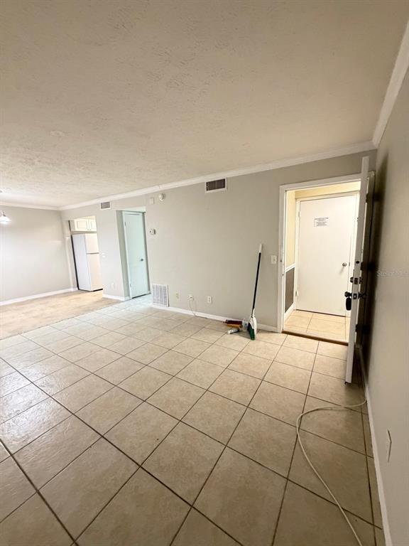 An interior view shows a tiled living area with a doorway leading to an exterior entrance — 13697 ORANGE SUNSET DRIVE UNIT 101, TAMPA, FL