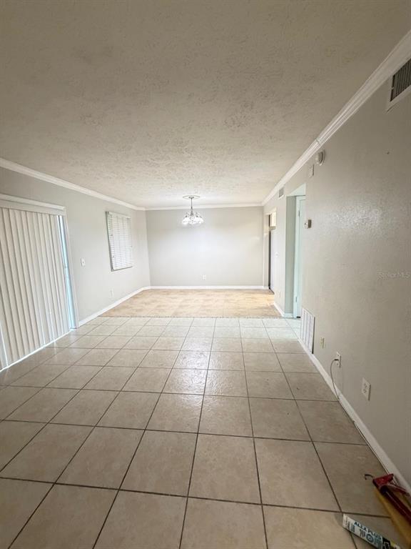 A room with light-colored tile flooring, white walls, and a sliding glass door — 13697 ORANGE SUNSET DRIVE UNIT 101, TAMPA, FL