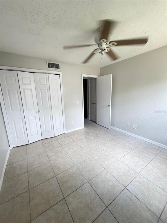 A bedroom with light-colored tile flooring, a ceiling fan, and white closet doors — 13697 ORANGE SUNSET DRIVE UNIT 101, TAMPA, FL