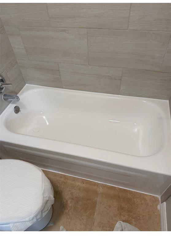 A white bathtub is installed against a wall with light-colored, horizontal rectangular tiles — 13697 ORANGE SUNSET DRIVE UNIT 101, TAMPA, FL