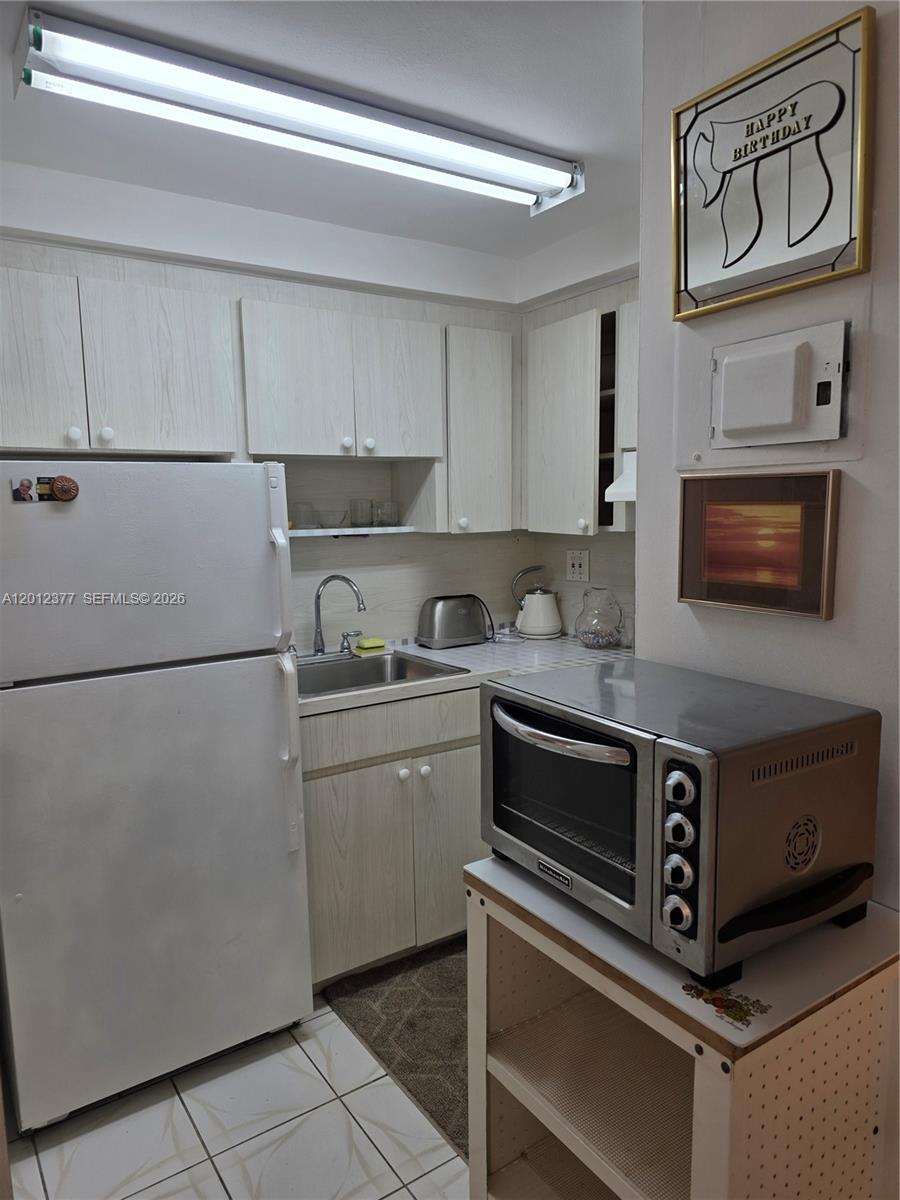 A small kitchen features light wood-grain cabinets, white appliances, and a countertop toaster oven — 2001 S Ocean Dr # 15, Hallandale Beach FL 33009, HALLANDALE BEACH, FL