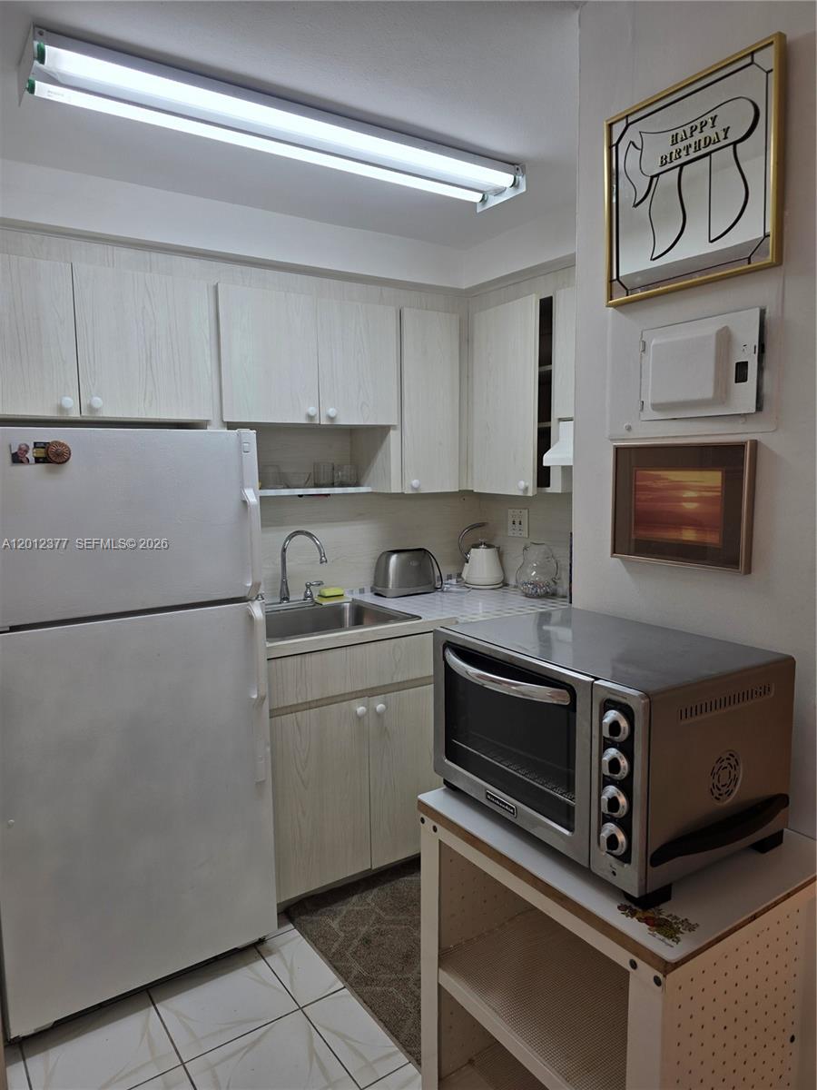 A small kitchen features white cabinets, a refrigerator, a stainless steel sink, and a toaster oven — 2001 S Ocean Dr # 15, Hallandale Beach FL 33009, HALLANDALE BEACH, FL