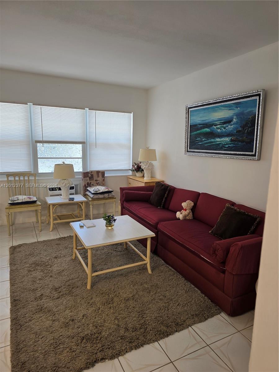 A living room features a red sofa, a coffee table, and a large ocean painting — 2001 S Ocean Dr # 15, Hallandale Beach FL 33009, HALLANDALE BEACH, FL