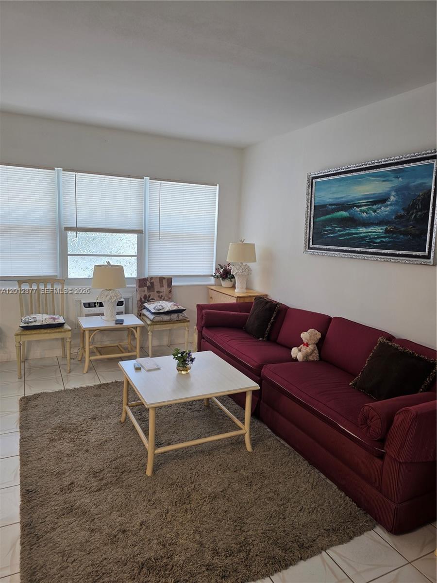 A living room features a maroon sofa, a coffee table, and a large ocean painting — 2001 S Ocean Dr # 15, Hallandale Beach FL 33009, HALLANDALE BEACH, FL