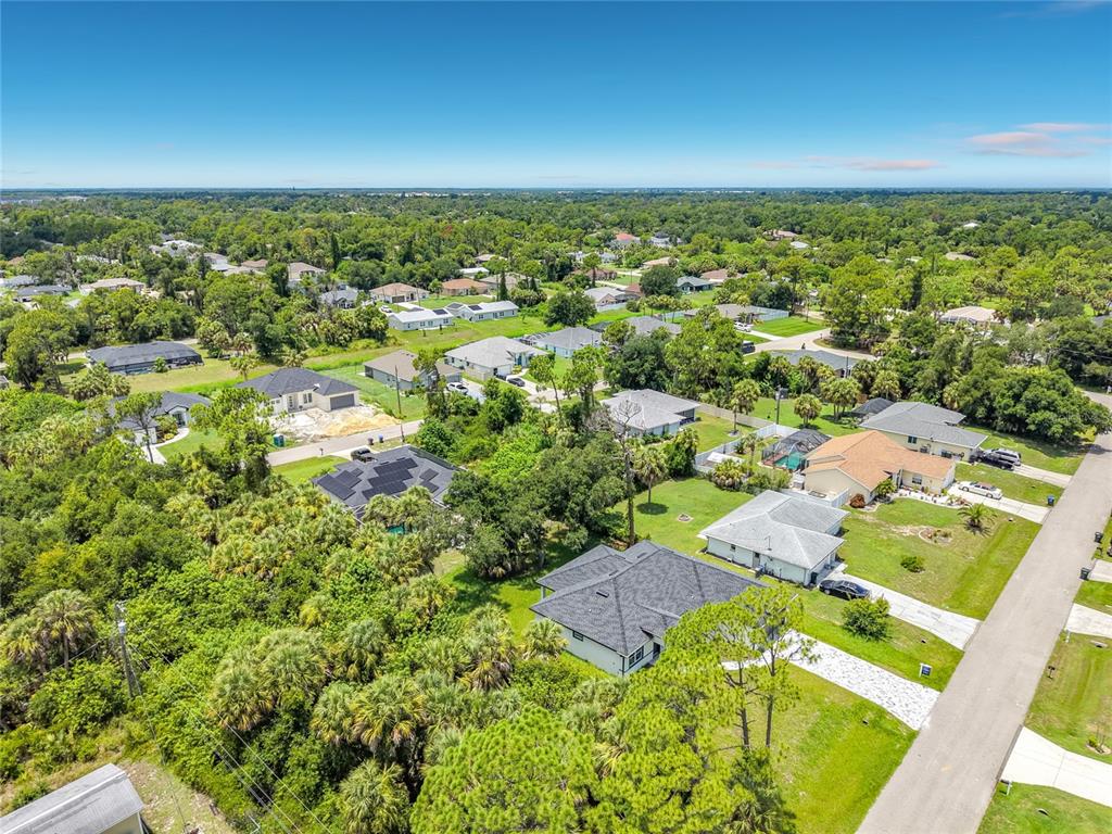 An aerial view shows a suburban neighborhood with single-family homes surrounded by dense green trees — 2607 SEAGULL LANE, NORTH PORT, FL