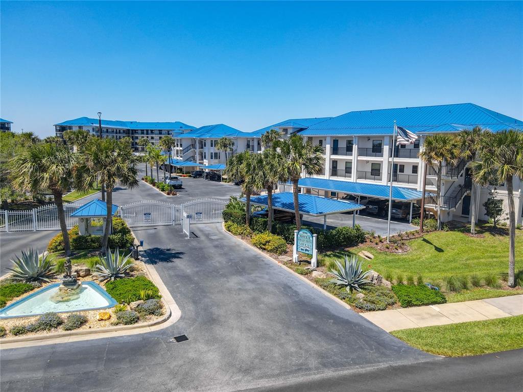 An aerial view shows a multi-building apartment complex with blue roofs, parking, and tennis courts — 2700 N PENINSULA AVENUE UNIT 536, NEW SMYRNA BEACH, FL