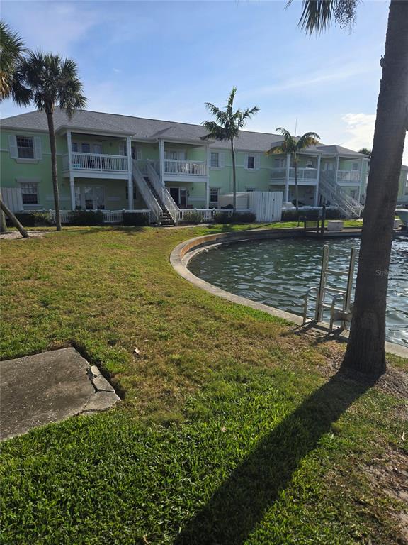 A multi-story light green apartment building sits beside a curved canal with a metal ladder — 5231 BEACH DRIVE SE UNIT A, ST PETERSBURG, FL