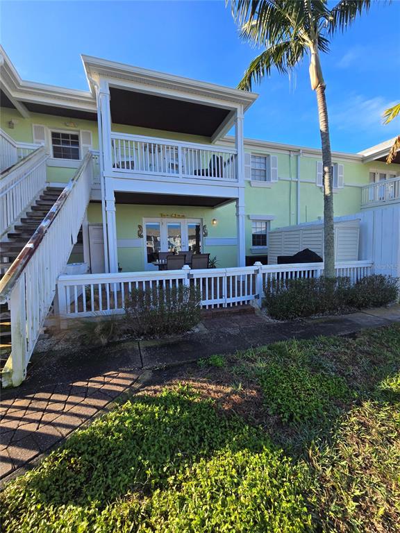 A two-story building with a white balcony, a ground-level patio, and an outdoor staircase — 5231 BEACH DRIVE SE UNIT A, ST PETERSBURG, FL