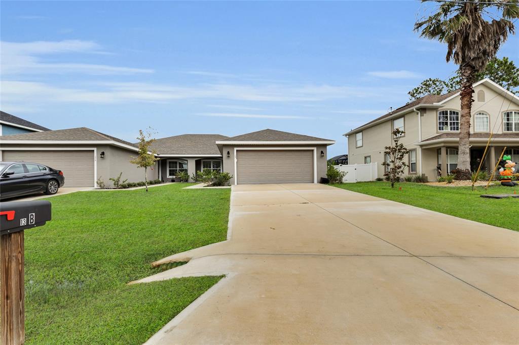 A single-story house with a two-car garage and a driveway sits on a grassy lot — 13 LLOVERA  PLACE, PALM COAST, FL