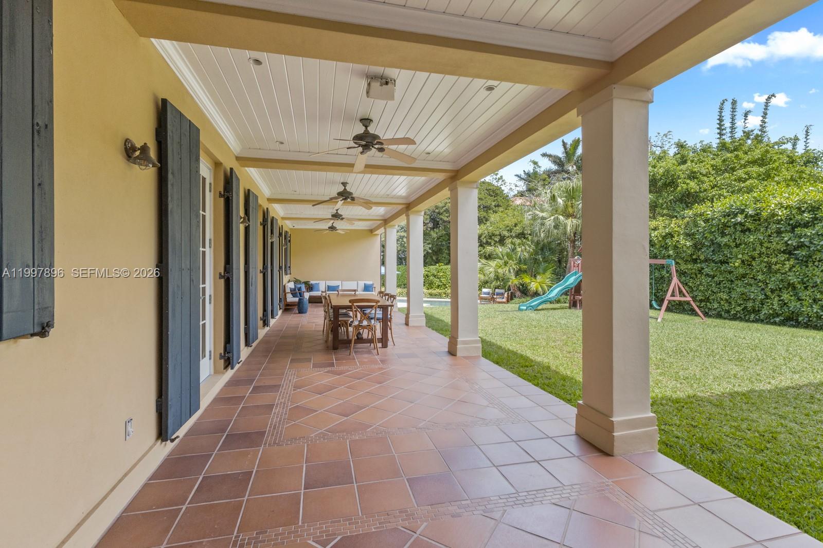 A covered patio features tiled flooring, ceiling fans, and a view of a grassy backyard — 685 Harbor Ln, Key Biscayne FL 33149, KEY BISCAYNE, FL