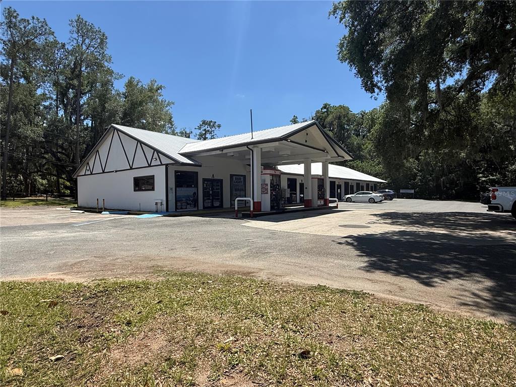 A white commercial building with a gas pump canopy stands in a paved parking lot — 3380 SE LAKE WEIR AVENUE UNIT G, OCALA, FL