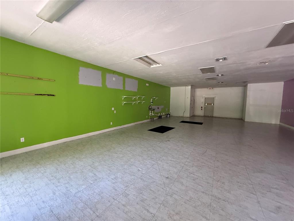 An empty commercial space features bright green walls, light-colored tile flooring, and a drop ceiling — 3380 SE LAKE WEIR AVENUE UNIT G, OCALA, FL