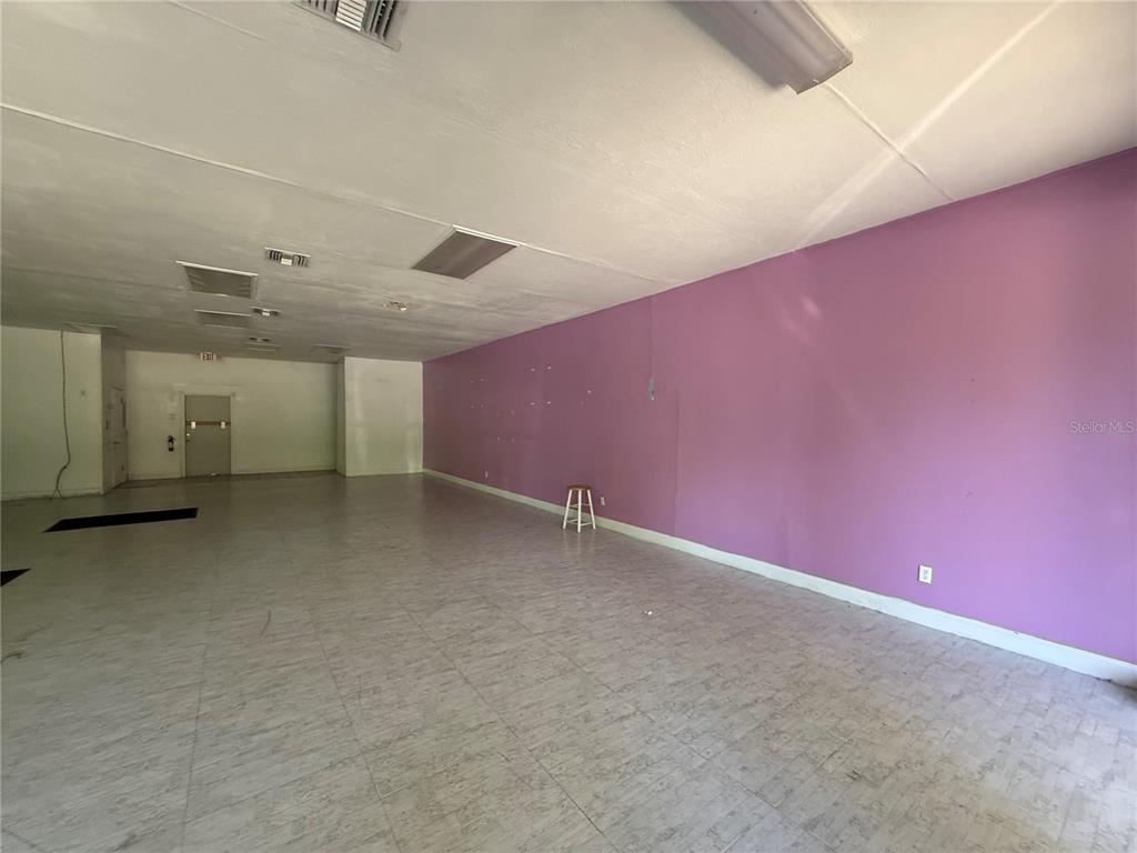 An empty commercial space features light-colored tile flooring and a long purple wall — 3380 SE LAKE WEIR AVENUE UNIT G, OCALA, FL