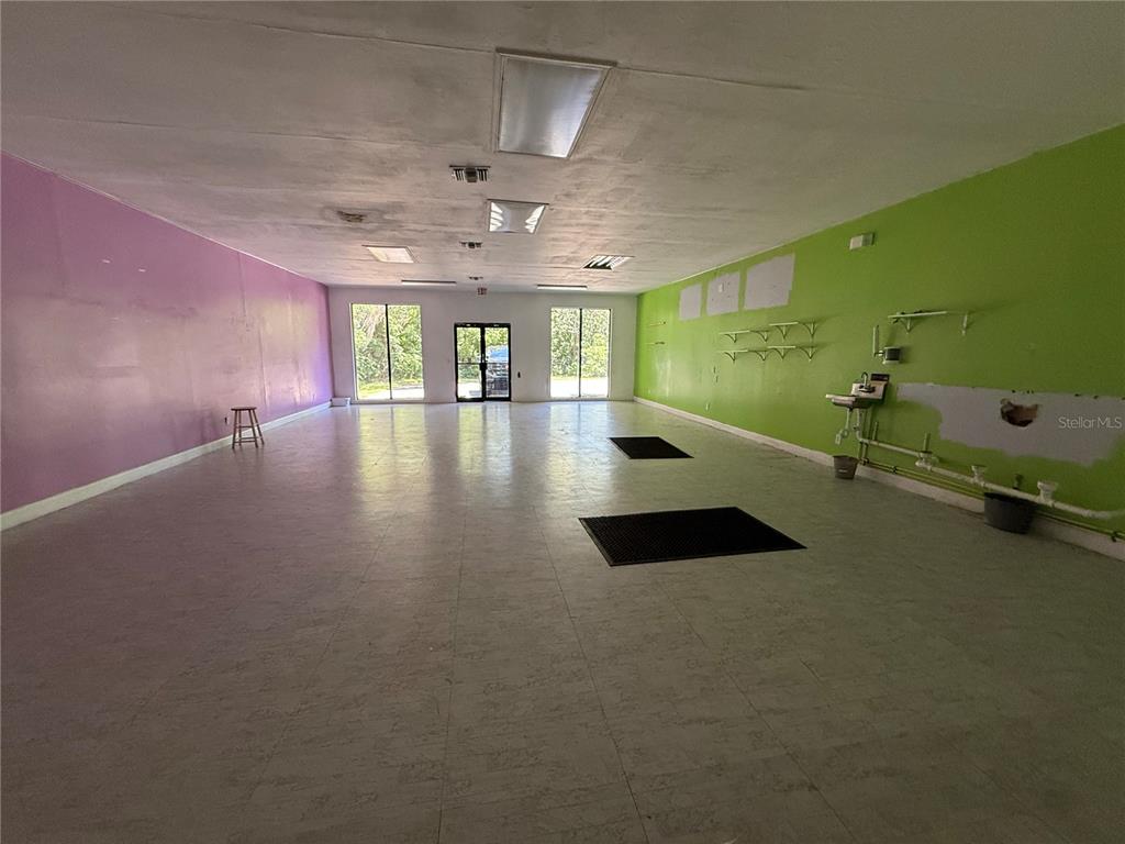An empty commercial space features purple and green walls, tile flooring, and a drop ceiling — 3380 SE LAKE WEIR AVENUE UNIT G, OCALA, FL