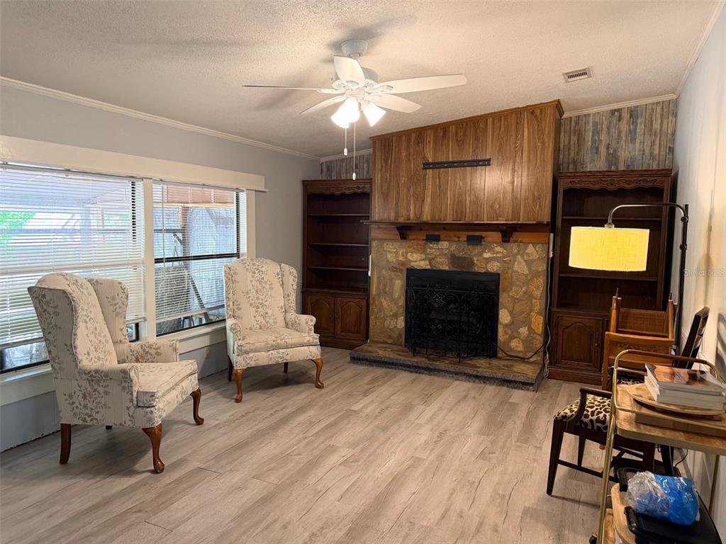 A living room features a stone fireplace, wood paneling, built-in shelving, and two floral armchairs — 14790 NW 72ND COURT, CHIEFLAND, FL