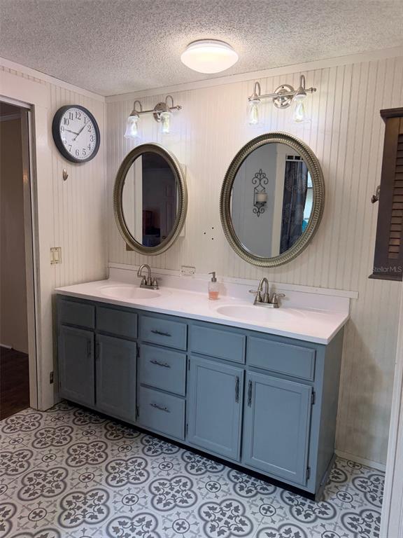 A bathroom features a double vanity with gray cabinets, oval mirrors, and patterned floor tiles — 14790 NW 72ND COURT, CHIEFLAND, FL